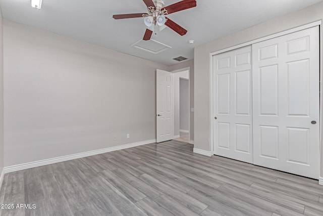 unfurnished bedroom with attic access, baseboards, light wood-type flooring, visible vents, and a closet