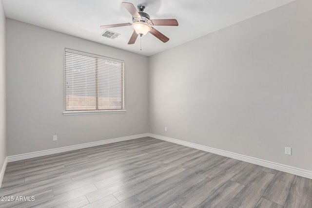unfurnished room featuring baseboards, ceiling fan, wood finished floors, and visible vents