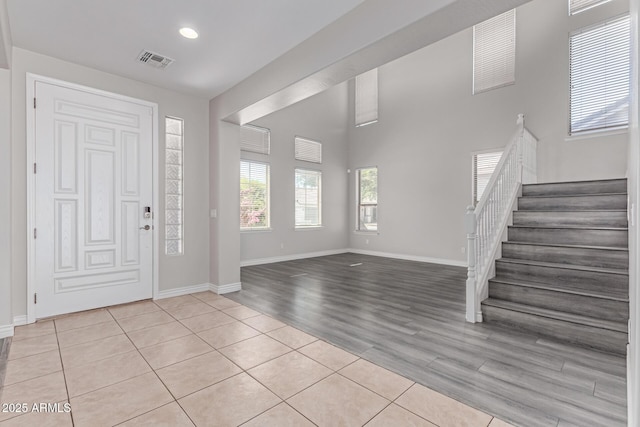 foyer with light tile patterned floors, baseboards, stairs, and visible vents