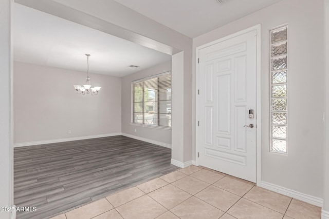 foyer featuring an inviting chandelier, baseboards, light wood-style flooring, and visible vents