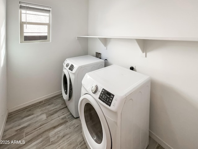 washroom featuring laundry area, baseboards, light wood finished floors, and separate washer and dryer