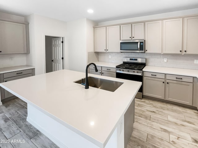 kitchen featuring stainless steel appliances, tasteful backsplash, gray cabinets, and a sink