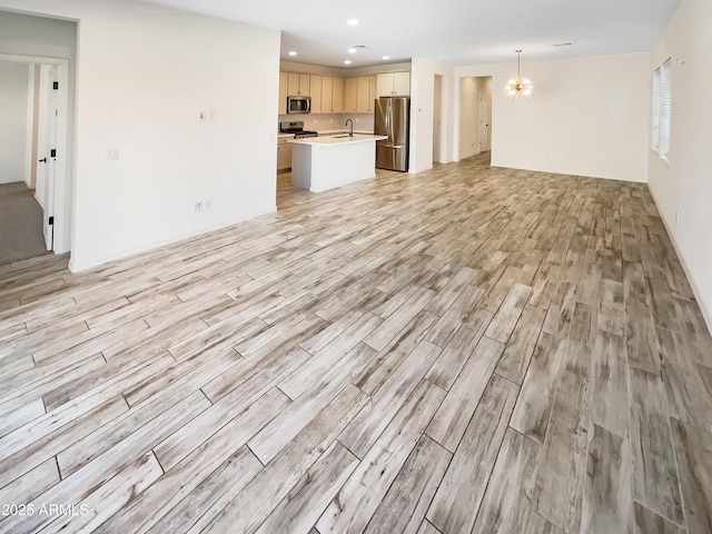 unfurnished living room featuring a chandelier, a sink, light wood-style flooring, and recessed lighting