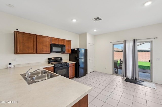 kitchen featuring brown cabinets, light countertops, visible vents, a sink, and black appliances