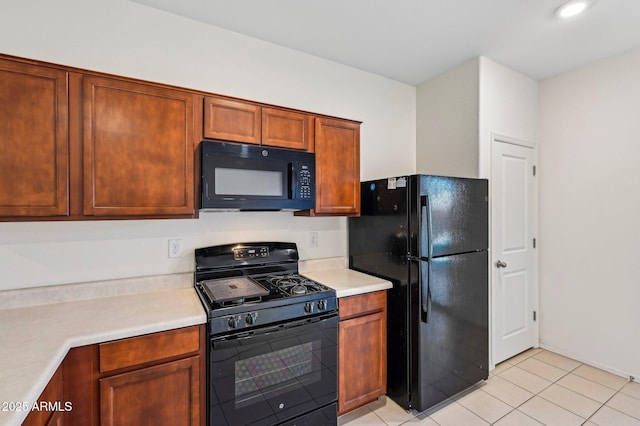 kitchen featuring black appliances, brown cabinetry, light tile patterned flooring, and light countertops