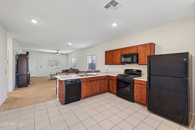 kitchen featuring open floor plan, a peninsula, light countertops, black appliances, and a sink