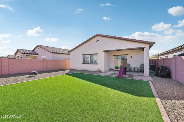 rear view of property featuring a yard, a fenced backyard, a patio, and stucco siding