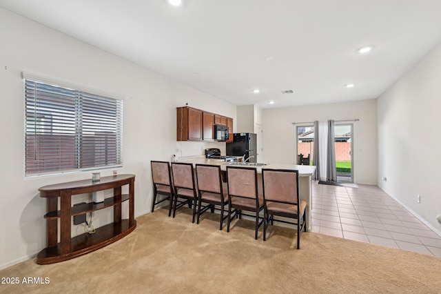 kitchen with light colored carpet, black microwave, light countertops, and a peninsula