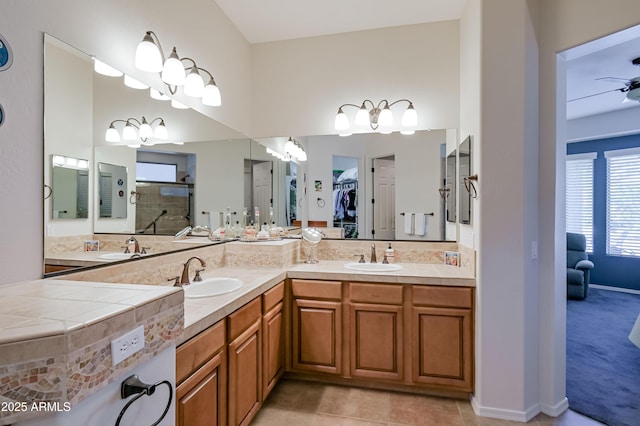 full bathroom with a sink, tile patterned flooring, a walk in closet, and a tile shower