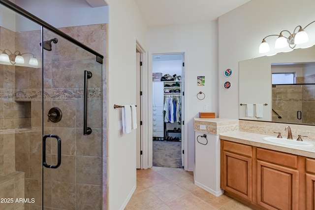 bathroom with tile patterned floors, a spacious closet, a shower stall, and vanity