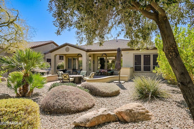 rear view of property featuring a patio, stucco siding, outdoor lounge area, a ceiling fan, and a tiled roof