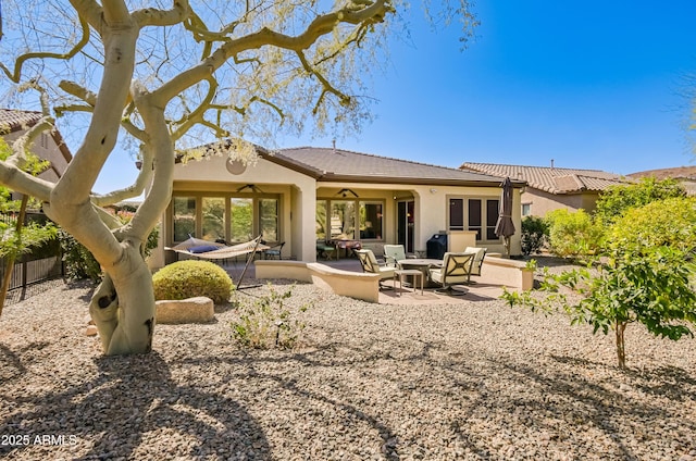 rear view of house with stucco siding, ceiling fan, fence, and a patio