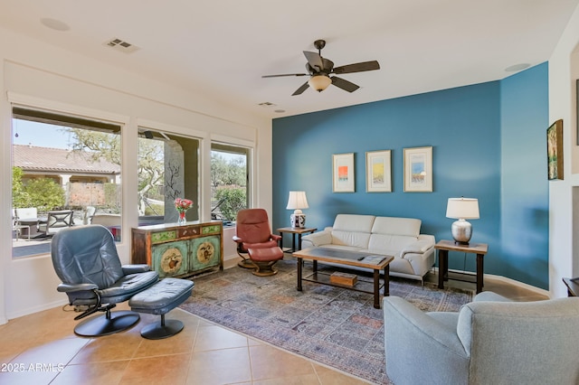 living area featuring a ceiling fan, visible vents, baseboards, and tile patterned floors