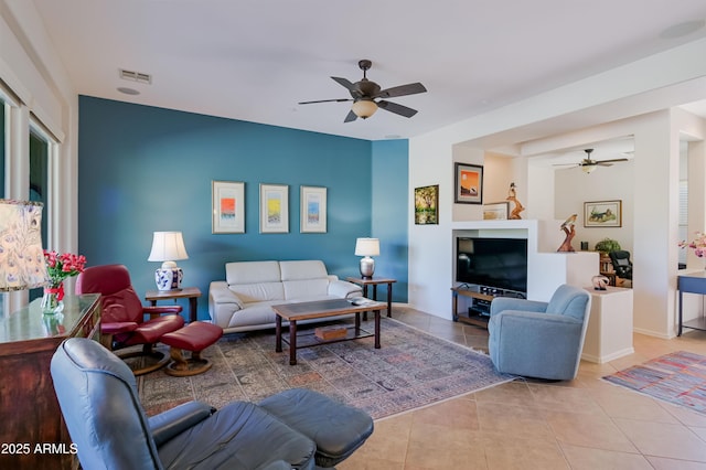 living room featuring light tile patterned floors, baseboards, visible vents, and a ceiling fan