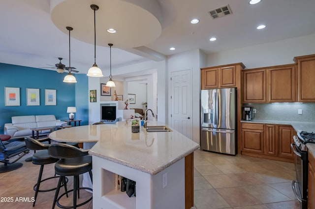 kitchen featuring visible vents, an island with sink, appliances with stainless steel finishes, open floor plan, and a sink