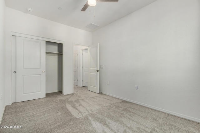 unfurnished bedroom featuring ceiling fan, light carpet, and a closet