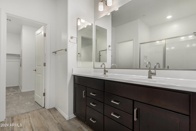 bathroom with hardwood / wood-style floors, vanity, and a shower with door