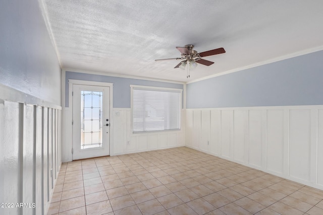 spare room featuring a textured ceiling, ceiling fan, light tile patterned floors, and crown molding