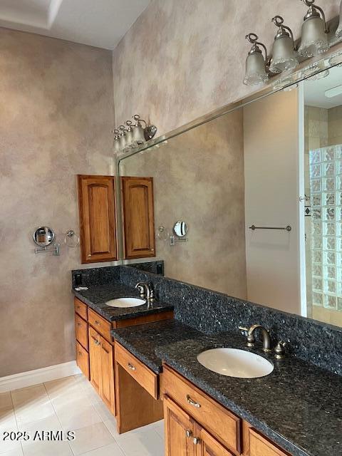 bathroom featuring tile patterned floors, a sink, baseboards, and double vanity