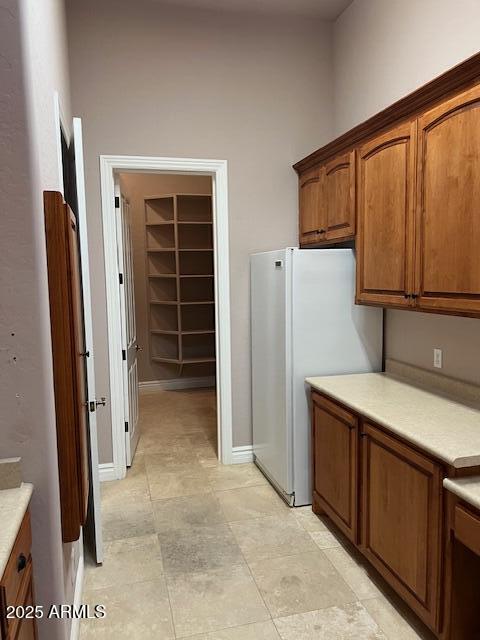 kitchen featuring brown cabinetry, light countertops, and freestanding refrigerator