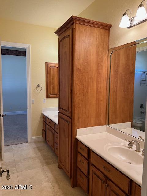 bathroom with a tub to relax in, tile patterned floors, baseboards, and vanity