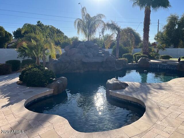 view of pool featuring a pool with connected hot tub, fence, and a patio