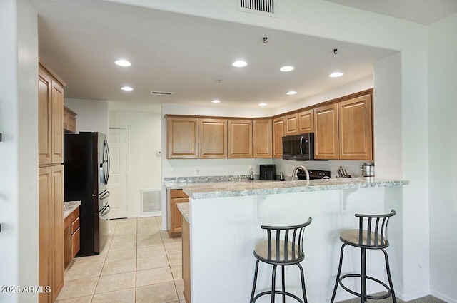 19700 N 76th St Unit 1058, Scottsdale, AZ 85255 - kitchen featuring refrigerator with ice dispenser, visible vents, black microwave, and a peninsula