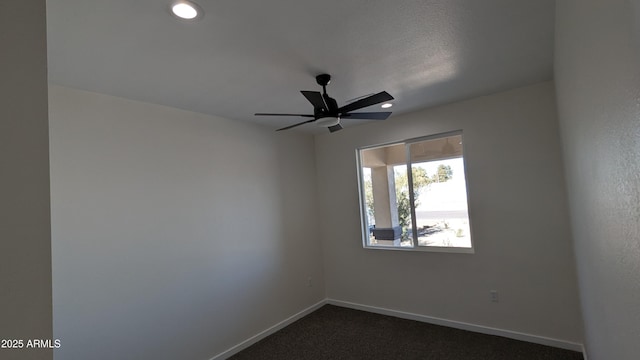 spare room featuring ceiling fan, dark carpet, and a textured ceiling