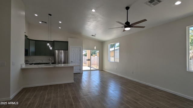 kitchen featuring light stone countertops, pendant lighting, stainless steel fridge, vaulted ceiling, and ceiling fan