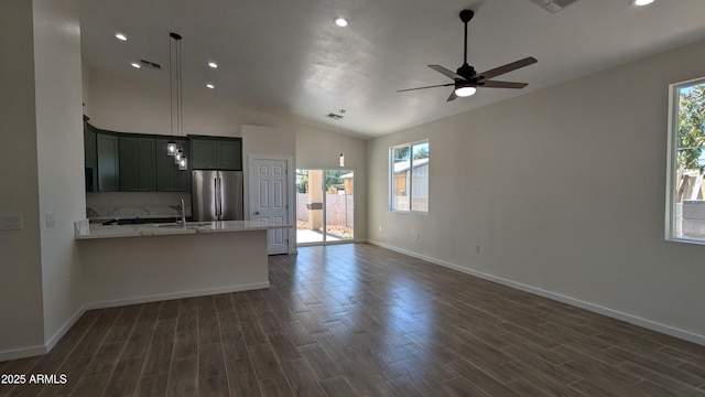 kitchen featuring sink, stainless steel refrigerator, vaulted ceiling, ceiling fan, and light stone counters