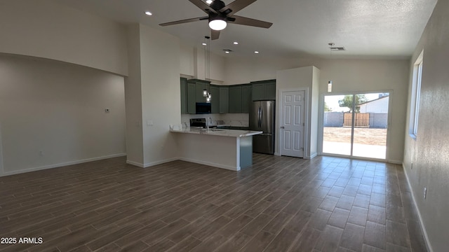 kitchen featuring a towering ceiling, sink, kitchen peninsula, stainless steel refrigerator, and ceiling fan