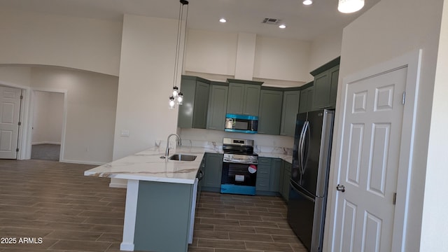 kitchen featuring decorative light fixtures, kitchen peninsula, a kitchen bar, sink, and appliances with stainless steel finishes