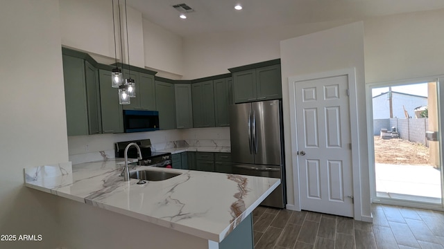 kitchen featuring light stone counters, decorative light fixtures, appliances with stainless steel finishes, and kitchen peninsula