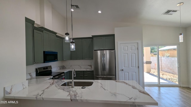 kitchen with pendant lighting, appliances with stainless steel finishes, sink, light stone counters, and green cabinets