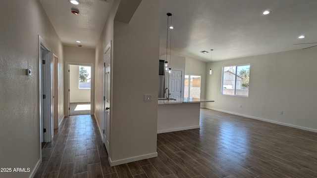 kitchen featuring hanging light fixtures, white cabinets, vaulted ceiling, and an island with sink