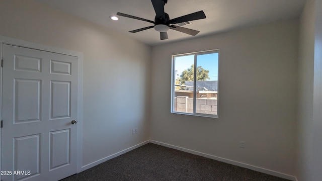 unfurnished room with ceiling fan and dark colored carpet