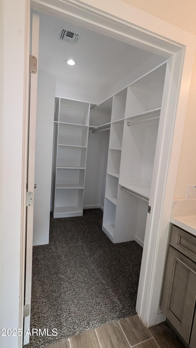 walk in closet featuring dark carpet