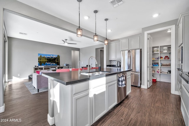 kitchen featuring white cabinetry, sink, stainless steel appliances, dark hardwood / wood-style flooring, and a kitchen island with sink