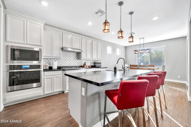 kitchen featuring sink, white cabinets, stainless steel appliances, and a center island with sink