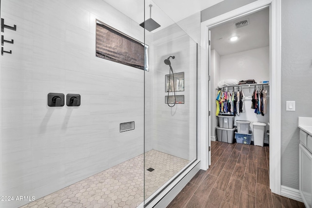 bathroom with a tile shower and vanity