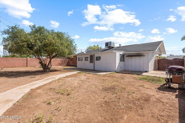 back of property featuring board and batten siding, a gate, central AC, a fenced backyard, and a patio