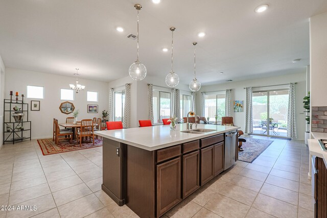 kitchen with dark brown cabinets, an island with sink, stainless steel dishwasher, pendant lighting, and sink