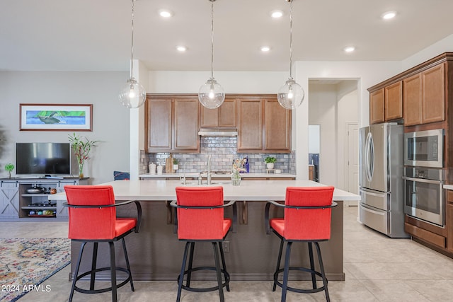 kitchen with appliances with stainless steel finishes, a kitchen breakfast bar, backsplash, and a center island with sink