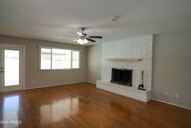 unfurnished living room featuring a brick fireplace, a textured ceiling, wood-type flooring, and ceiling fan