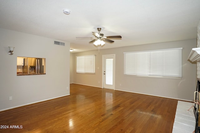 unfurnished living room featuring a fireplace, hardwood / wood-style floors, and ceiling fan