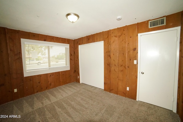 carpeted empty room featuring wooden walls