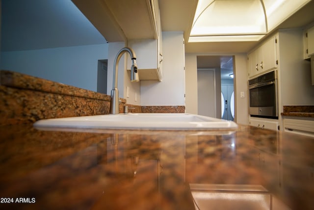 kitchen with stainless steel oven, sink, and white cabinets