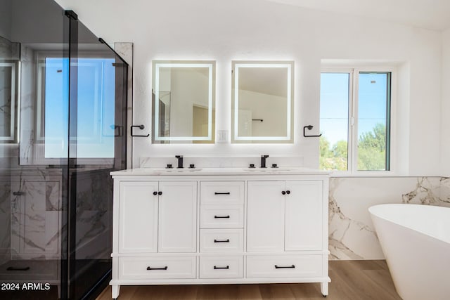 bathroom with vanity, independent shower and bath, vaulted ceiling, and wood-type flooring