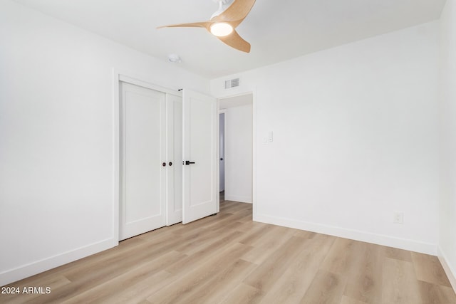 unfurnished bedroom with a closet, light wood-type flooring, and ceiling fan