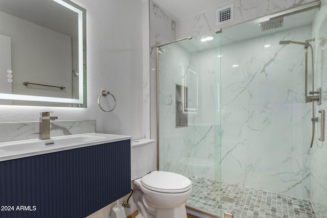 bathroom featuring vanity, a shower with shower door, and toilet